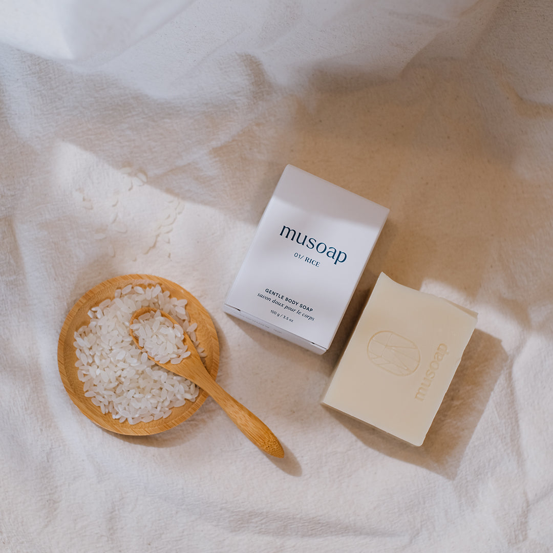 Flat lay image of Rice Gentle Body Soap with raw rice on a plate