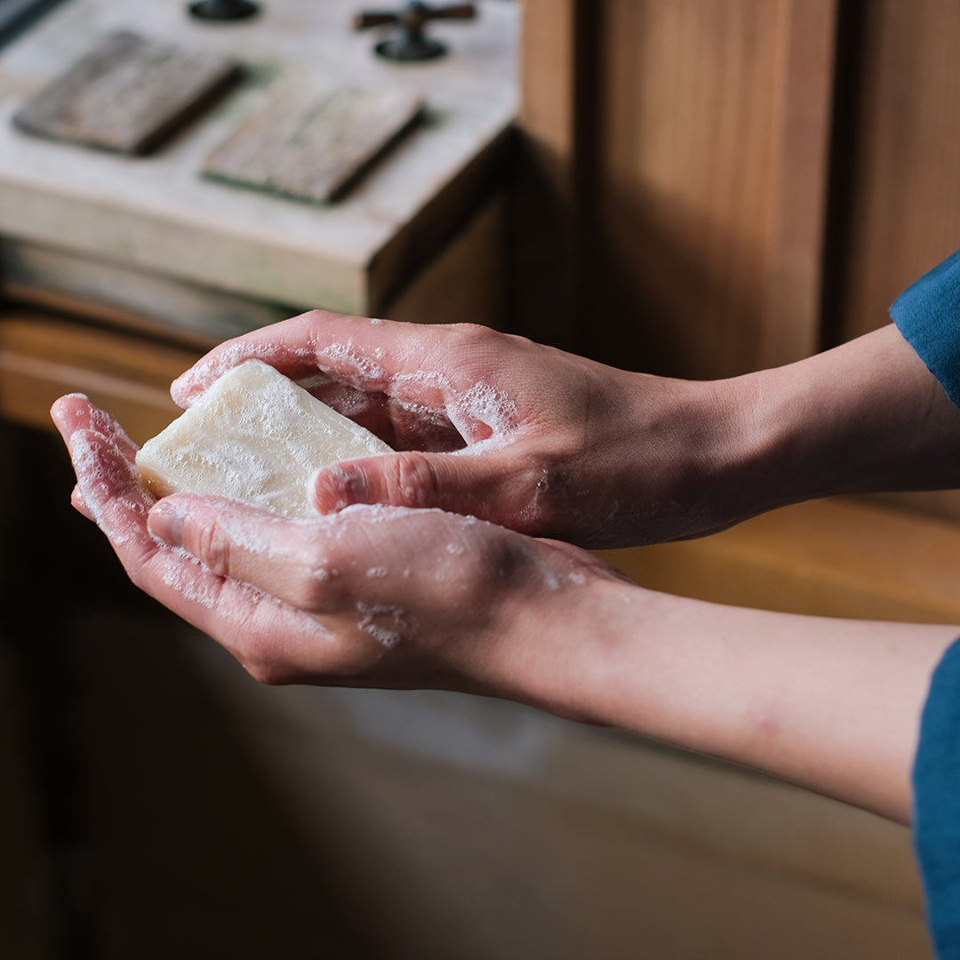 A pair of hands holding a sudsy natural bar soap
